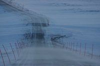 Wind blows snow across road